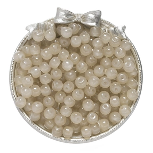 Detail of 8x7mm beige glass apple beads in a silver tray for DIY jewelry making