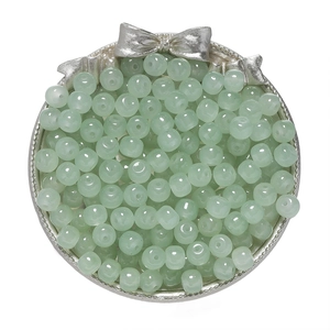 Close-up of translucent mint green glass apple beads in a decorative silver tray for DIY