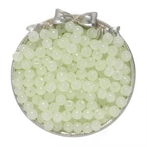 Macro view of light green glass apple beads on a silver tray for DIY jewelry making