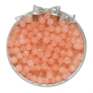 Macro detail of glossy pink glass apple beads on a silver tray for DIY jewelry