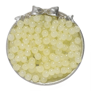 Macro shot of pale yellow semi-translucent apple beads in a decorative silver metal tray
