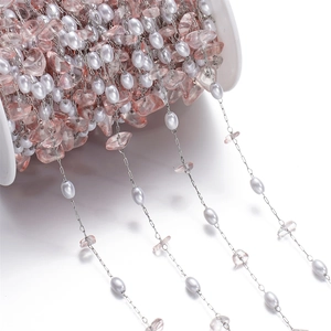 Detail of DIY jewelry chain with pink irregular stones and white oval pearls on spool
