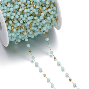Macro detail of blue glass beads and gold beads on a stainless steel jewelry DIY chain