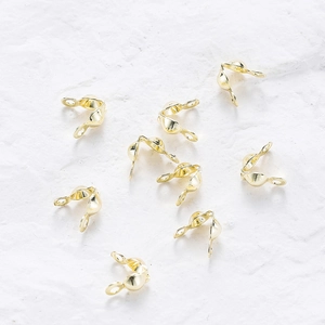 Macro detail of rose gold fold-over crimp bead connectors for DIY jewelry making