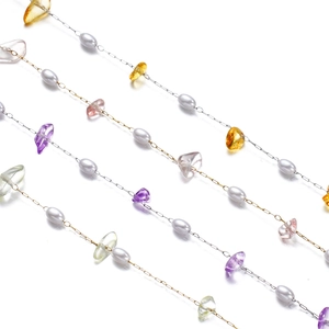 Detailed macro of irregular colorful gemstones and pearls on a fine stainless steel chain