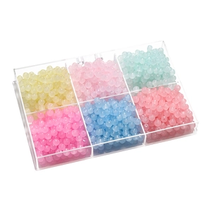 Close-up of frosted glass apple beads in a six-compartment organizer for DIY jewelry