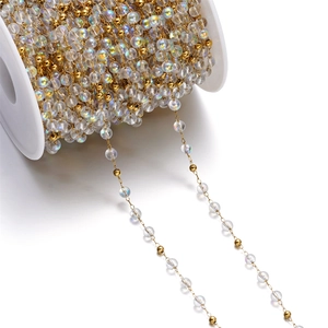 Detail of colorful cat-eye glass beads and gold stainless steel DIY jewelry chain on a spool