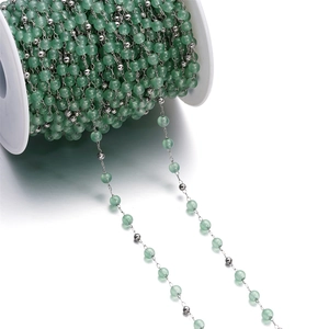 Detail of light green cat eye glass beads on a stainless steel chain DIY jewelry spool