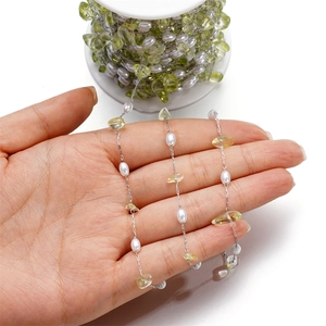 Detail of green gemstone chips and white pearls on stainless steel chain for jewelry DIY