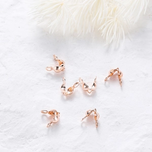 Macro shot of rose gold bead tips calottes for DIY jewelry making on white background