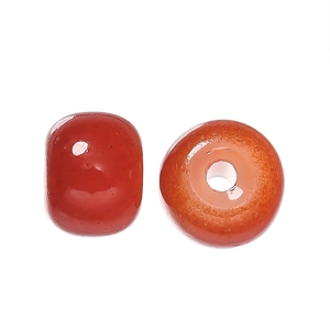 Macro detail of two orange-red apple-shaped glass beads with center holes for DIY jewelry