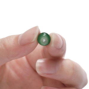 Close-up of translucent green apple-shaped glass bead with center hole for DIY jewelry