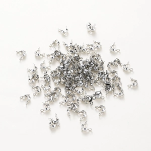 Macro shot of silver clamshell bead tips for DIY jewelry making on white background