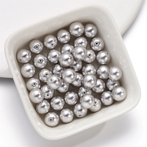 Silver grey round crystal glass pearl beads with threading holes in a white bowl