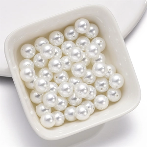 Close-up of high-luster white round loose glass pearls in a white ceramic dish