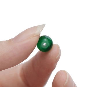 Makroaufnahme einer kleinen dunkelgrünen Glasperle mit Loch für DIY-Schmuckherstellung