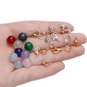 Makroaufnahme bunter Glasperlen und Metallzubehör für Schmuck in einer Handfläche