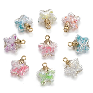 Close-up of star shaped glass pendants with colorful glitter sand and gold metal loops