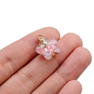 Close-up of a luminous star-shaped glass pendant filled with pink glitter and gold ring