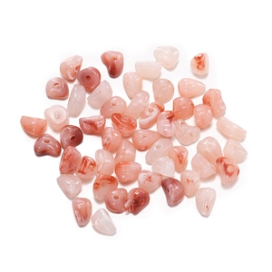 Macro shot of irregular heart-shaped acrylic beads with pink marble ink patterns