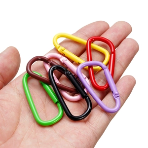 Dettaglio di moschettoni a forma di D in alluminio colorato tenuti in mano