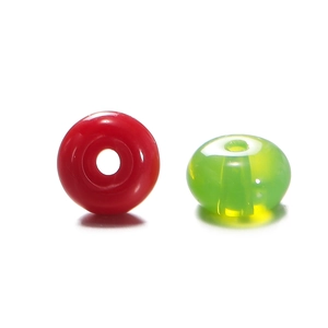 Close-up of polished red and translucent green flat glass abacus beads for DIY crafts