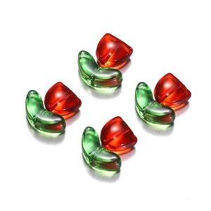 Macro detail of translucent red cherry acrylic beads with green leaves for DIY jewelry crafts