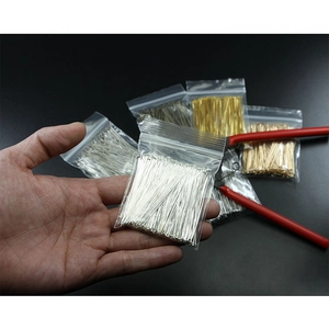 Λεπτομέρεια από καρφίτσες κοσμημάτων DIY σε ασημί, χρυσό και μπρονζέ με κόκκινη πένσα