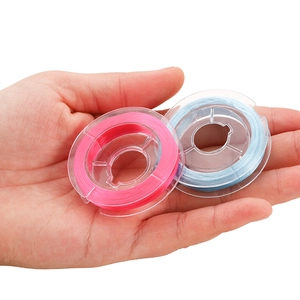 Close-up of rose red and light blue elastic crystal strings on mini transparent spools