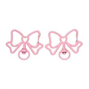 Detail van roze strikvormige sleutelhangers met matte afwerking en hartvormige metalen details