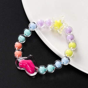 Detailopname van kleurrijke acryl kralenarmband met gele ster en roze hart hangers