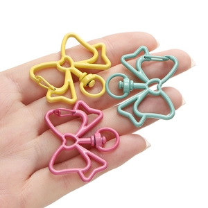 Gekleurde legering strik sleutelhanger haken in roze cyaan geel vastgehouden in hand