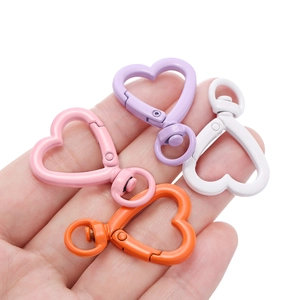 Chiusure a molla a cuore da 26mm in rosa, viola, bianco e arancione tenute in mano
