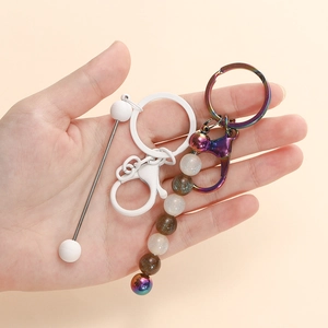 DIY keychain set with gradient star beads and white metal rings on beige background