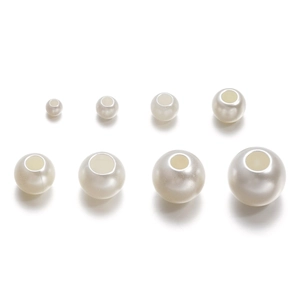 Détail de perles barils en ABS blanc cassé à gros trous pour la création de bijoux DIY