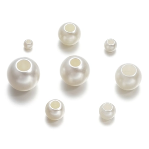 Gros plan de perles d'imitation blanches de tailles variées avec trous pour le DIY