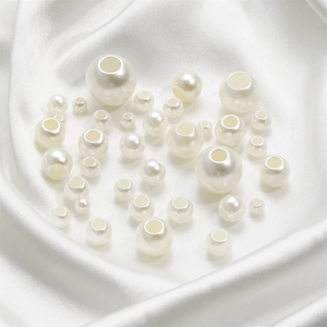Gros plan de perles d'imitation ABS blanc crème à gros trous sur un tissu en soie blanc