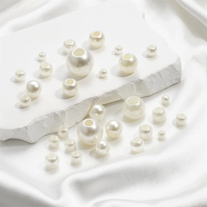 Gros plan de perles d'imitation ABS blanc cassé sur tissu en soie pour bijoux DIY