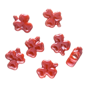 Macro detail of red clover-shaped glazed ceramic beads for DIY jewelry making with side holes