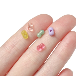 Detail of 4mm colorful peanut shaped acrylic beads for DIY jewelry making on fingertips