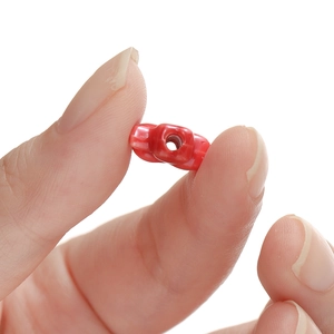 Red clover-shaped glazed ceramic bead held by fingers for DIY jewelry bracelets
