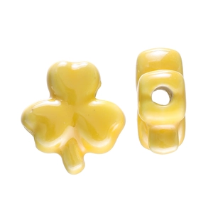 Macro shot of glossy yellow clover ceramic beads showing shape and through-hole structure