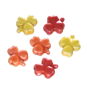 Close-up of glazed ceramic clover beads in red and yellow for DIY jewelry making