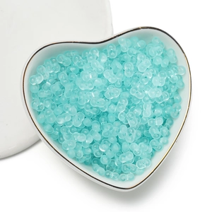 Detailed view of mint blue dumbbell-shaped acrylic beads in a heart porcelain dish