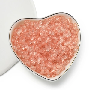 Close-up of 4mm peach acrylic peanut beads for DIY jewelry making in a heart-shaped plate