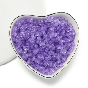 Macro detail of purple matte acrylic double-hole peanut beads in a heart-shaped bowl