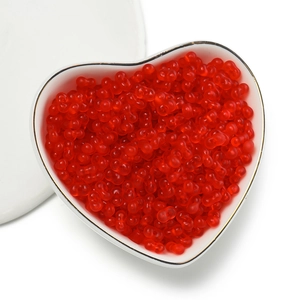 Macro shot of 4mm red translucent peanut beads in a heart dish for DIY jewelry making