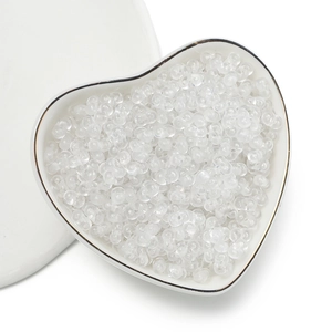 Macro view of clear 4mm acrylic peanut beads for DIY jewelry making in heart-shaped bowl