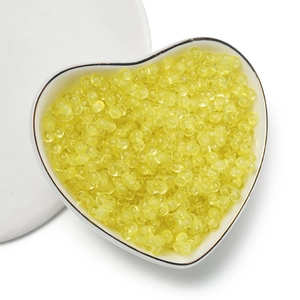 Macro shot of 4mm translucent yellow peanut beads in a heart-shaped ceramic dish