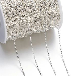 Macro detail of silver-colored 1.5mm bead chain on a white spool for DIY jewelry making